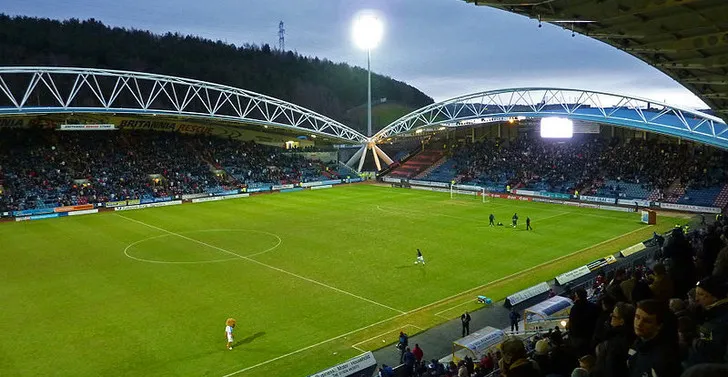 Ánh đèn pha rực sáng John Smith's Stadium trong trận đấu buổi tối