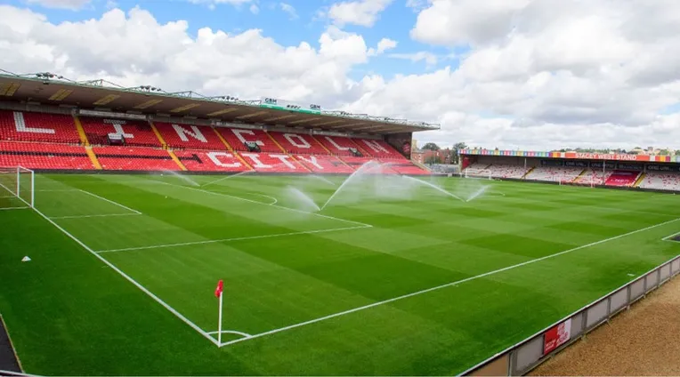 Góc nhìn cận cảnh mặt sân Sincil Bank, cho thấy thảm cỏ xanh mướt và khán đài chính