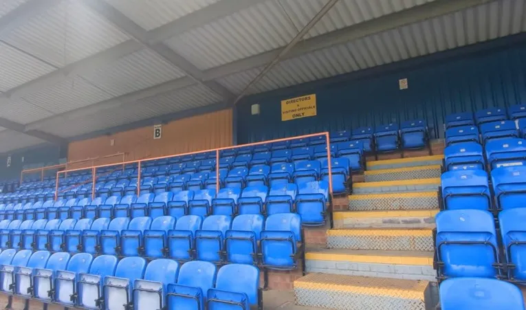 Khu vực ghế ngồi hiện đại tại khán đài chính sân Cressing Road, nơi cổ động viên Braintree Town theo dõi trận đấu